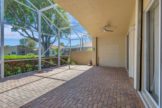 view of patio / terrace with glass enclosure, a ceiling fan, and a residential view