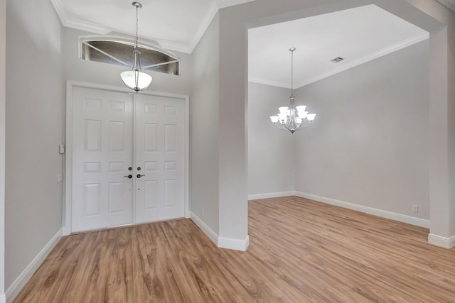 entryway with light wood-type flooring, baseboards, a chandelier, and crown molding
