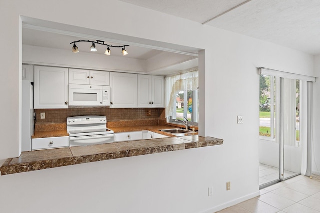 kitchen with white appliances, a sink, white cabinetry, decorative backsplash, and plenty of natural light