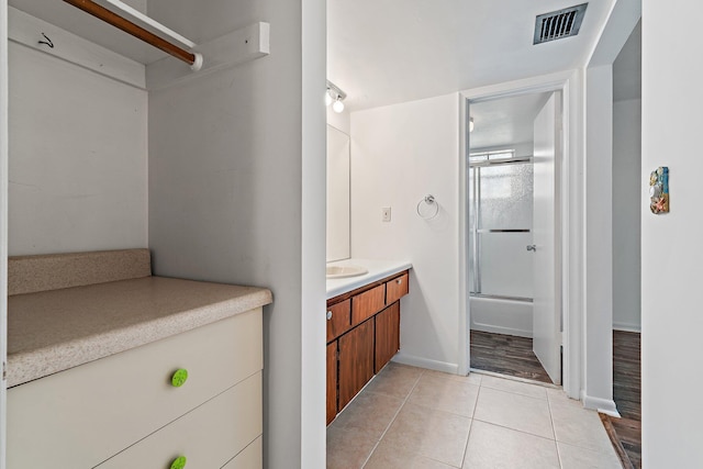 full bath featuring vanity, enclosed tub / shower combo, tile patterned flooring, and baseboards