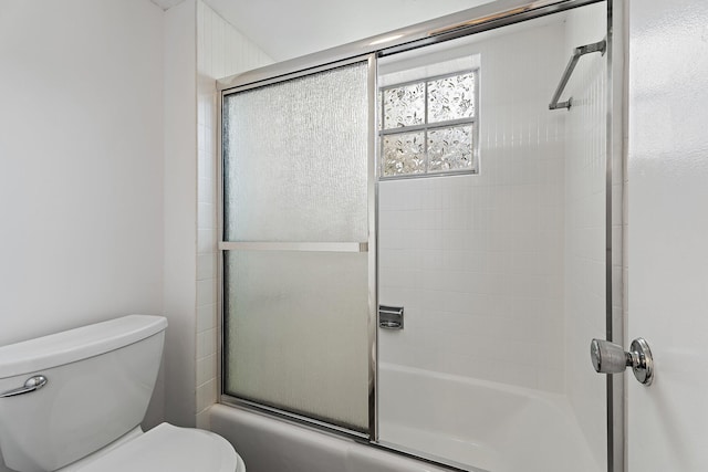 bathroom with combined bath / shower with glass door and toilet