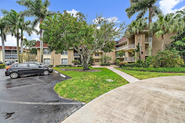 surrounding community featuring uncovered parking and a lawn
