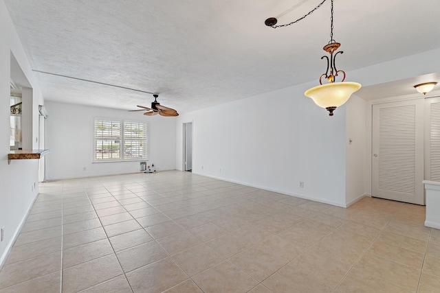 unfurnished living room with a ceiling fan, light tile patterned flooring, and baseboards