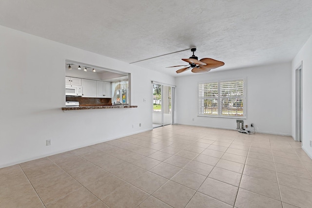 unfurnished living room featuring light tile patterned floors, ceiling fan, and a textured ceiling