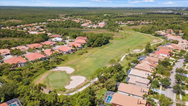 view of property location featuring a golf course, nearby suburban area, and a heavily wooded area