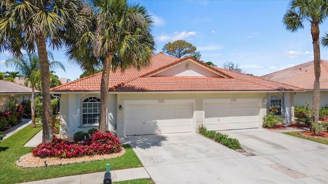mediterranean / spanish-style home featuring a tiled roof, concrete driveway, stucco siding, and an attached garage