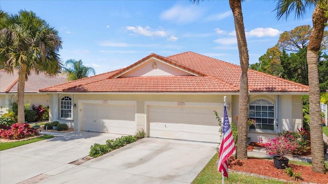 mediterranean / spanish-style home with a tile roof, a garage, concrete driveway, and stucco siding