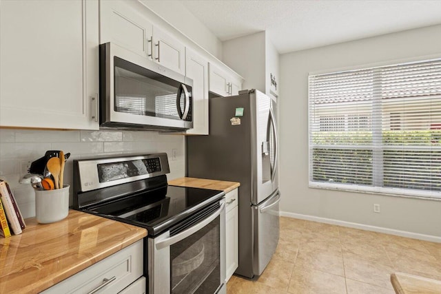kitchen featuring stainless steel appliances, white cabinets, baseboards, light countertops, and light tile patterned floors