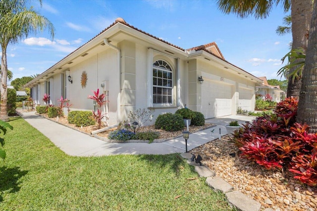 view of property exterior featuring a garage, a tile roof, concrete driveway, and a yard