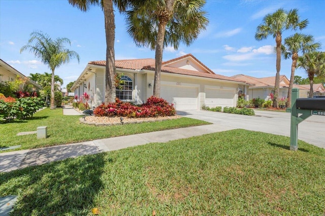 mediterranean / spanish house with an attached garage, concrete driveway, a tiled roof, a front yard, and stucco siding