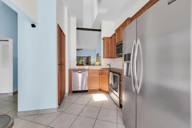 kitchen with appliances with stainless steel finishes, light tile patterned flooring, and a sink