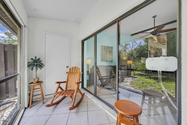 sunroom / solarium with tile patterned floors and a ceiling fan