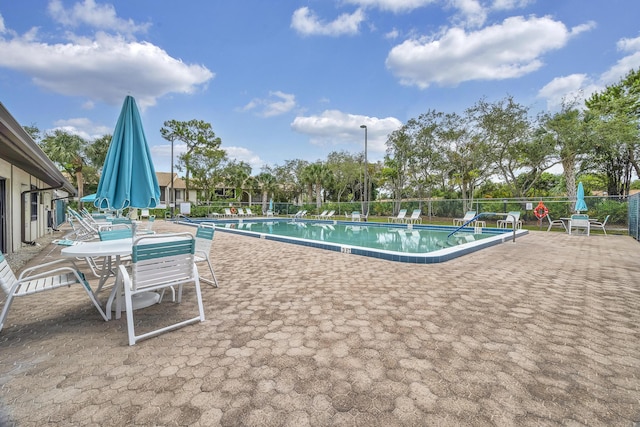 community pool with a patio area and fence