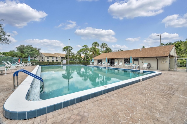 community pool with fence and a patio area