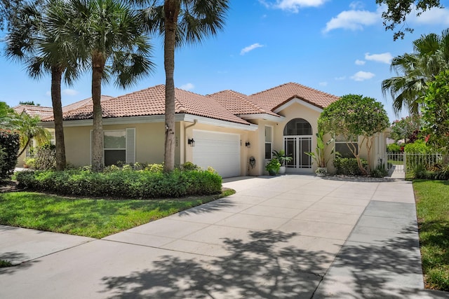 mediterranean / spanish-style house with stucco siding, a tiled roof, fence, an attached garage, and driveway