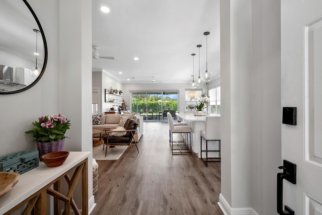 hall with ornamental molding, recessed lighting, wood finished floors, and baseboards