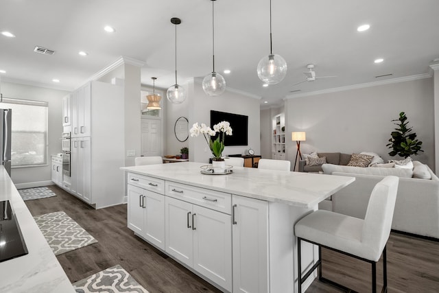 kitchen featuring ornamental molding, a ceiling fan, white cabinetry, recessed lighting, and a center island