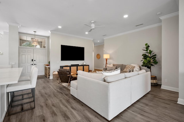 living area with baseboards, a ceiling fan, wood finished floors, recessed lighting, and ornamental molding