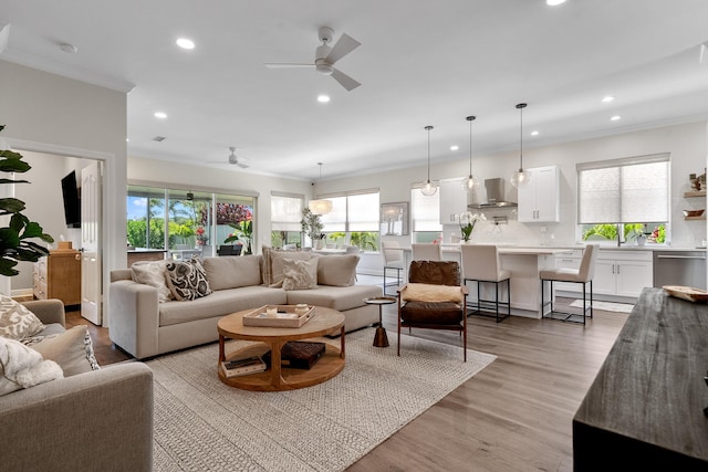 living room with a ceiling fan, recessed lighting, plenty of natural light, ornamental molding, and light wood-type flooring