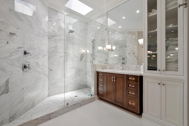 bathroom featuring a skylight, a marble finish shower, vanity, and tile patterned floors