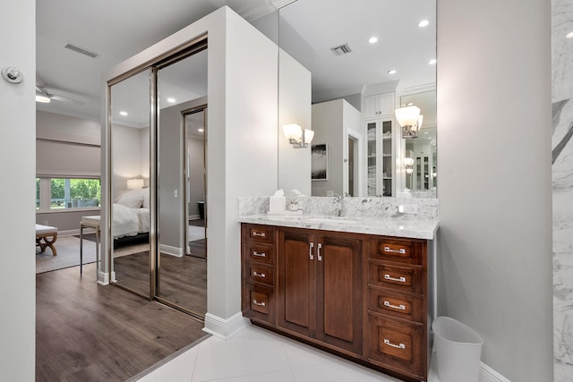ensuite bathroom with vanity, baseboards, recessed lighting, and wood finished floors