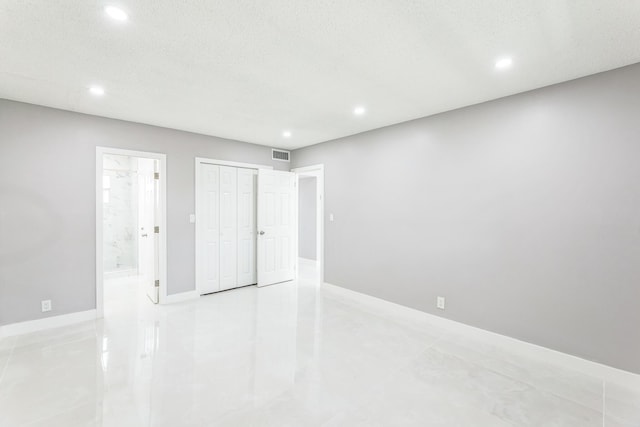 unfurnished bedroom with recessed lighting, ensuite bath, baseboards, a closet, and light tile patterned floors