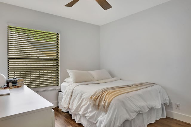 bedroom with dark wood-type flooring, a ceiling fan, and baseboards