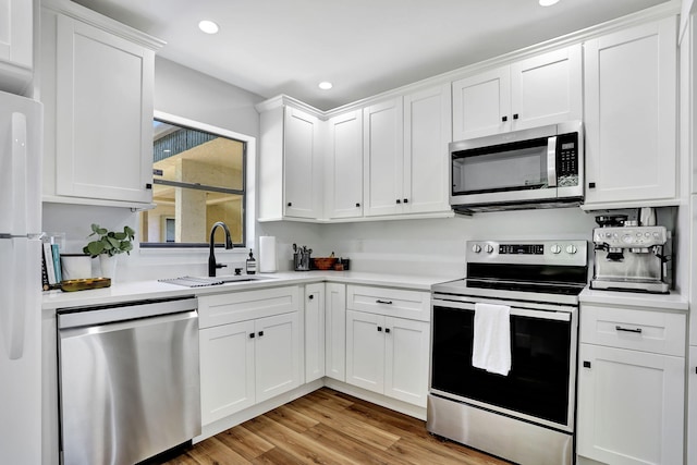 kitchen featuring appliances with stainless steel finishes, a sink, white cabinets, and recessed lighting