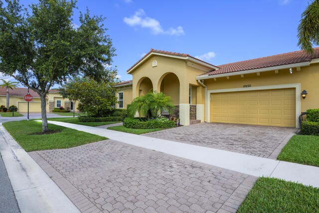10250 SW Azzo Ln, Port Saint Lucie, FL 34986 - mediterranean / spanish-style house with stucco siding, decorative driveway, a garage, and a tile roof