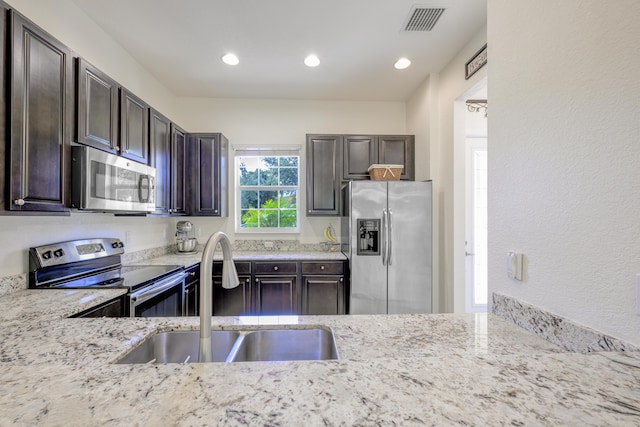 10250 SW Azzo Ln, Port Saint Lucie, FL 34986 - kitchen featuring appliances with stainless steel finishes, a sink, dark brown cabinetry, light stone counters, and recessed lighting