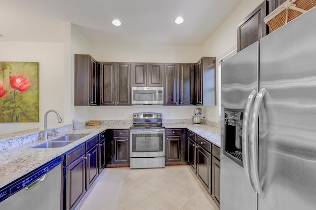10250 SW Azzo Ln, Port Saint Lucie, FL 34986 - kitchen with stainless steel appliances, a sink, dark brown cabinetry, light tile patterned floors, and light stone counters
