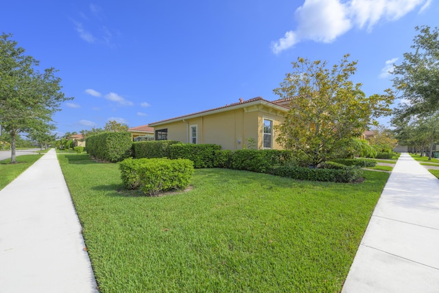 10250 SW Azzo Ln, Port Saint Lucie, FL 34986 - view of side of home featuring a yard, stucco siding, and a tile roof