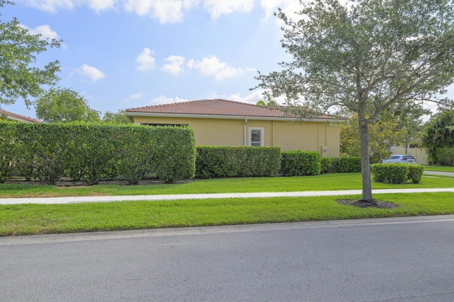 10250 SW Azzo Ln, Port Saint Lucie, FL 34986 - view of side of home with a tiled roof, a lawn, and stucco siding