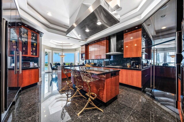 3066 SE Dune Dr, Stuart, FL 34996 - kitchen with granite floors, wall chimney exhaust hood, modern cabinets, a tray ceiling, and recessed lighting