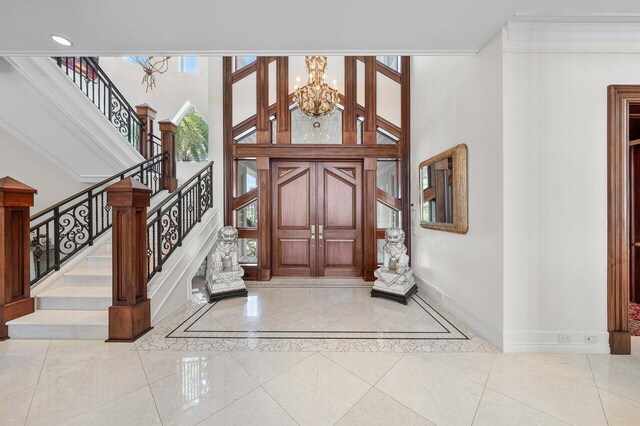 3066 SE Dune Dr, Stuart, FL 34996 - entryway featuring baseboards, a chandelier, stairway, a high ceiling, and inlaid floor details