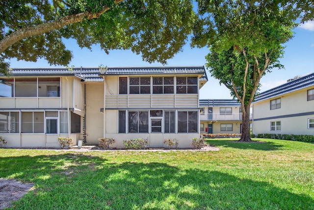 228 Brittany E, Delray Beach, FL 33446 - back of house featuring a lawn, a sunroom, and stucco siding