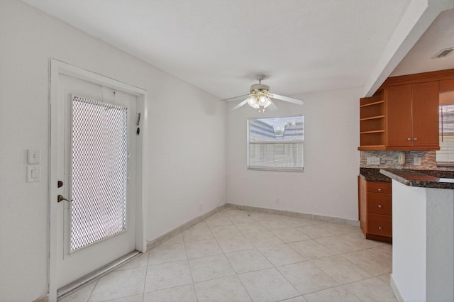 228 Brittany E, Delray Beach, FL 33446 - kitchen featuring brown cabinetry, open shelves, dark countertops, backsplash, and a ceiling fan