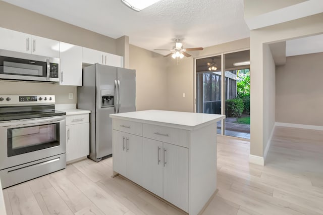 7655 Cinebar Dr Unit 105, Boca Raton, FL 33433 - kitchen featuring stainless steel appliances, a ceiling fan, light countertops, white cabinetry, and a center island