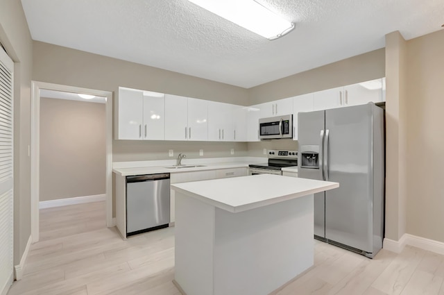 7655 Cinebar Dr Unit 105, Boca Raton, FL 33433 - kitchen featuring appliances with stainless steel finishes, a sink, white cabinets, light countertops, and a textured ceiling