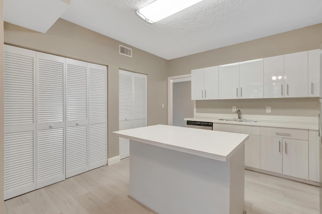 7655 Cinebar Dr Unit 105, Boca Raton, FL 33433 - kitchen with a sink, dishwasher, light countertops, light wood-type flooring, and white cabinetry
