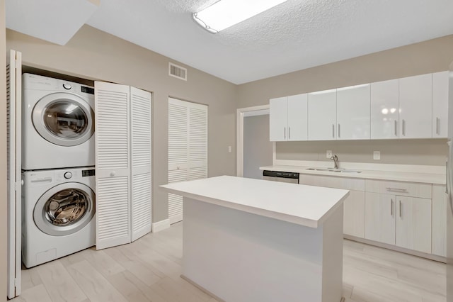 7655 Cinebar Dr Unit 105, Boca Raton, FL 33433 - washroom featuring stacked washer / dryer, a textured ceiling, and baseboards