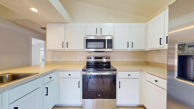 kitchen featuring stainless steel appliances, white cabinets, light countertops, recessed lighting, and vaulted ceiling