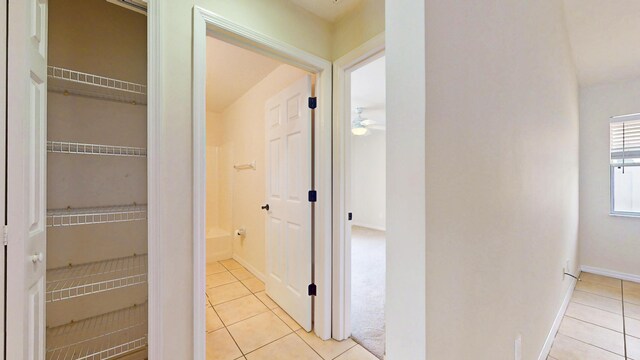 corridor featuring light tile patterned flooring and baseboards
