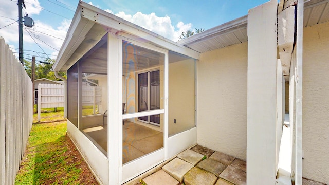 view of property exterior with a sunroom, fence, and stucco siding