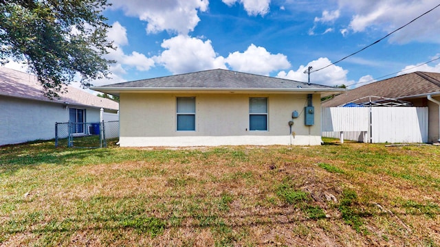 rear view of property with stucco siding and a gate
