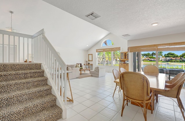 dining room featuring lofted ceiling, light tile patterned floors, stairs, a water view, and a textured ceiling