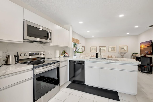 kitchen featuring stainless steel appliances, a peninsula, a sink, light tile patterned floors, and white cabinetry