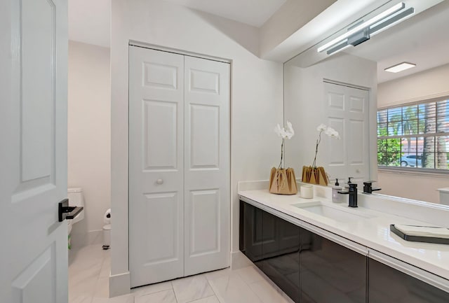 bathroom with a closet, vanity, toilet, and marble finish flooring