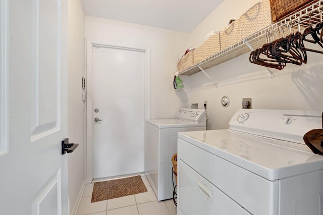washroom with washer and clothes dryer, light tile patterned floors, and baseboards
