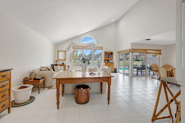dining area with healthy amount of natural light, high vaulted ceiling, a textured ceiling, and light tile patterned floors